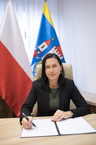 Sekretarz gminy Aleksandra Małysz-Pilch siedzi w swoim gabinecie. W tle flaga Polski i Skoczowa